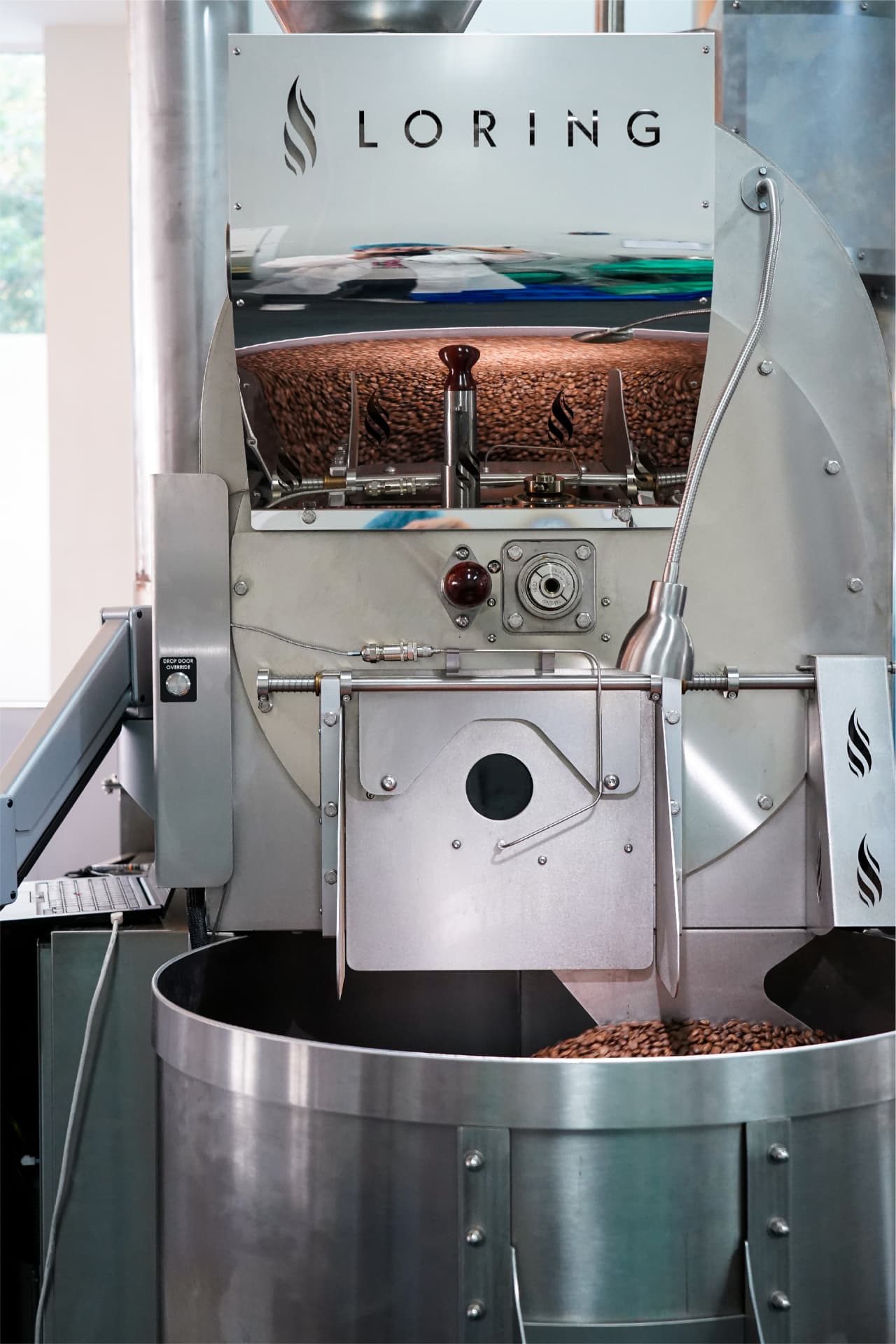 Roast profile curves on a laptop beside a drum roaster at Morse Coffee's roastery.